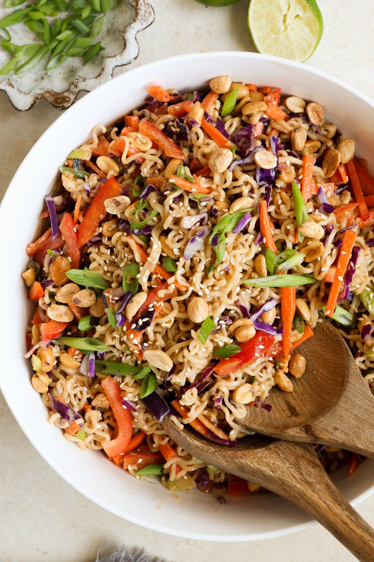 white bowl filled with an asian salad with ramen noodles, chopped veggies, and peanuts