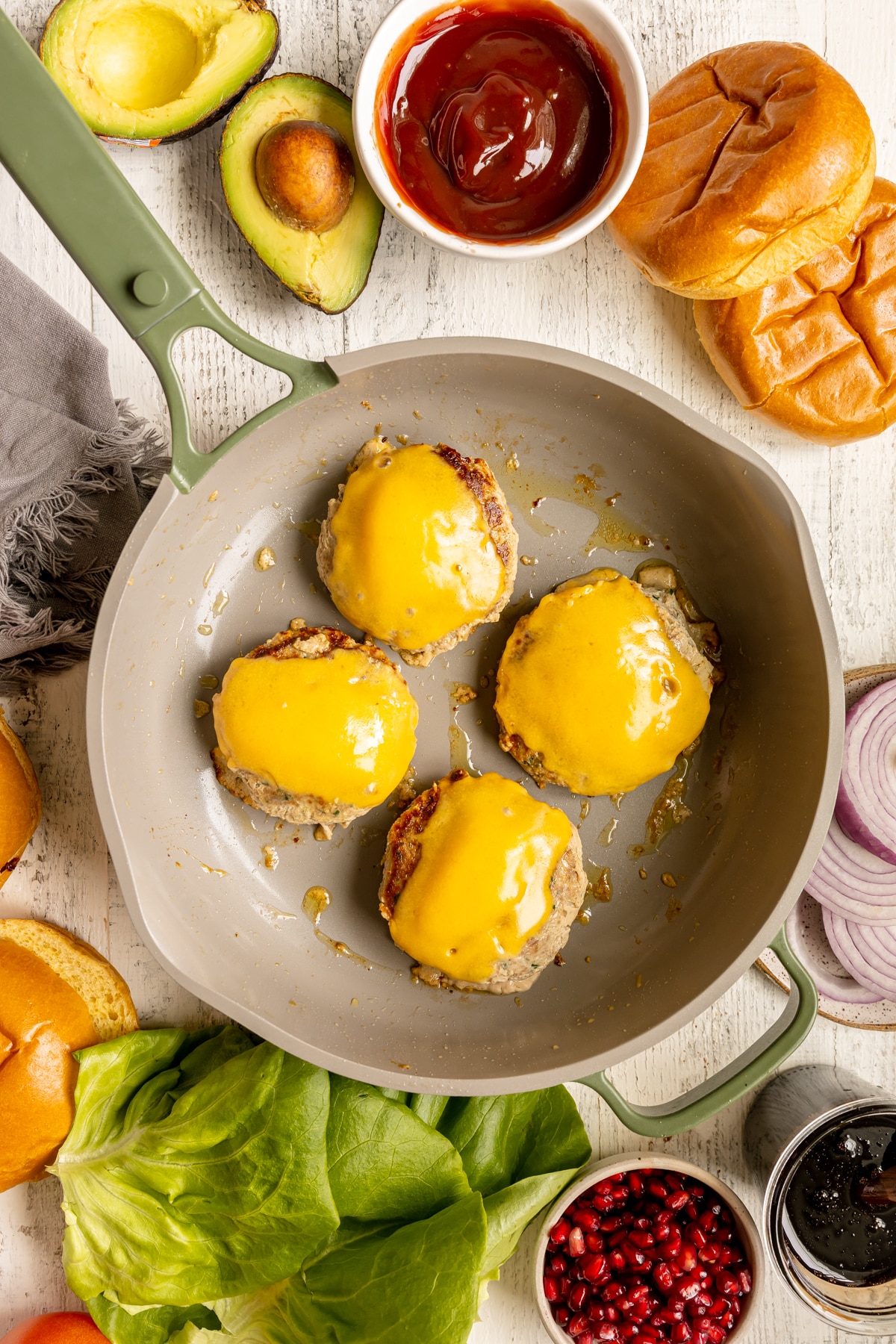 burgers in a skillet topped with cheddar cheese. 