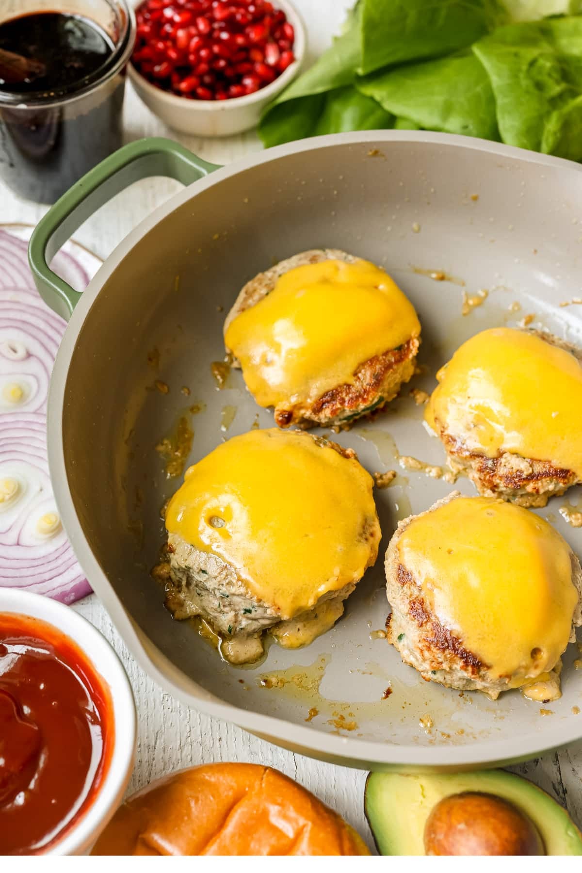 turkey burgers in a skillet topped with cheddar cheese. 
