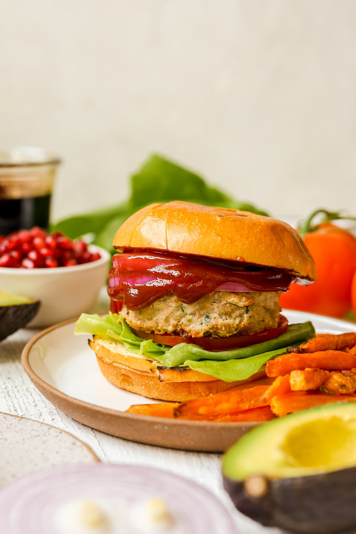 turkey burger on a white plate with sweet potato fries. 