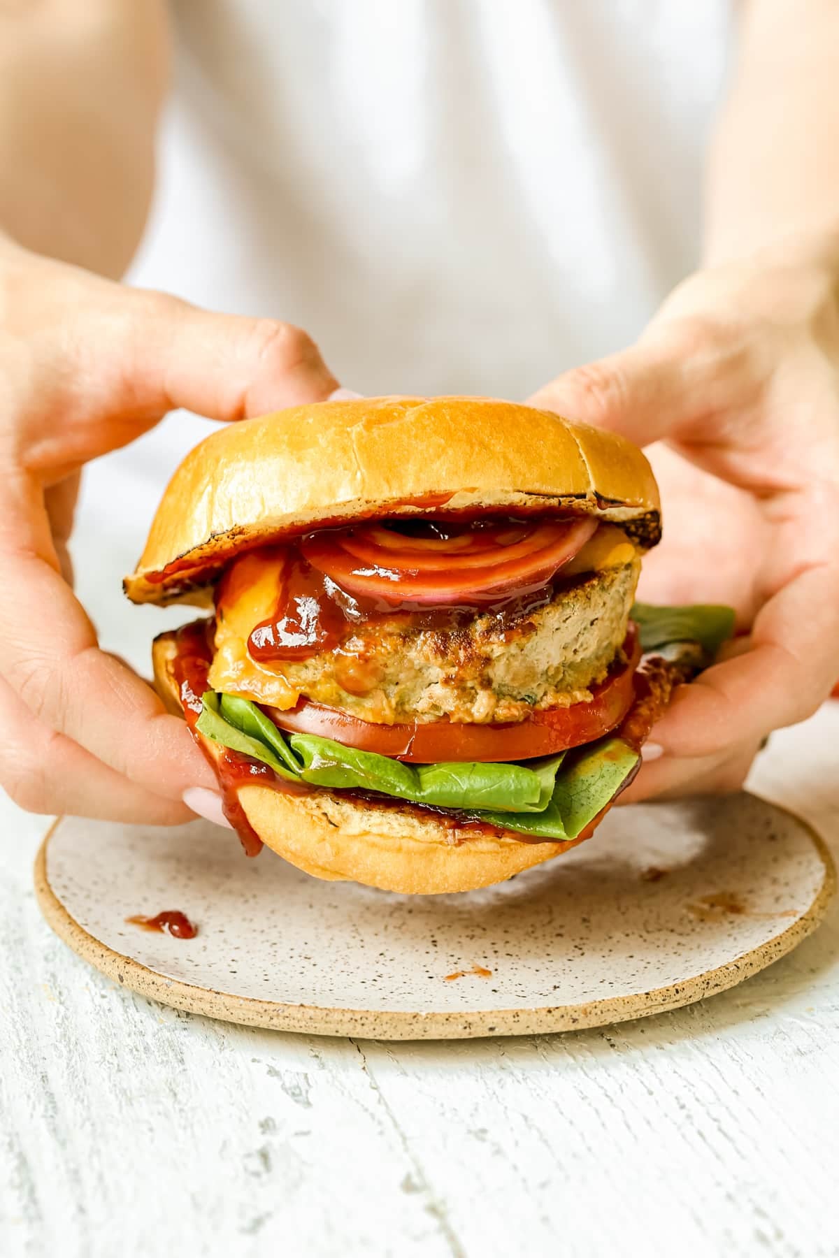 a womans hands holding a turkey burger. 