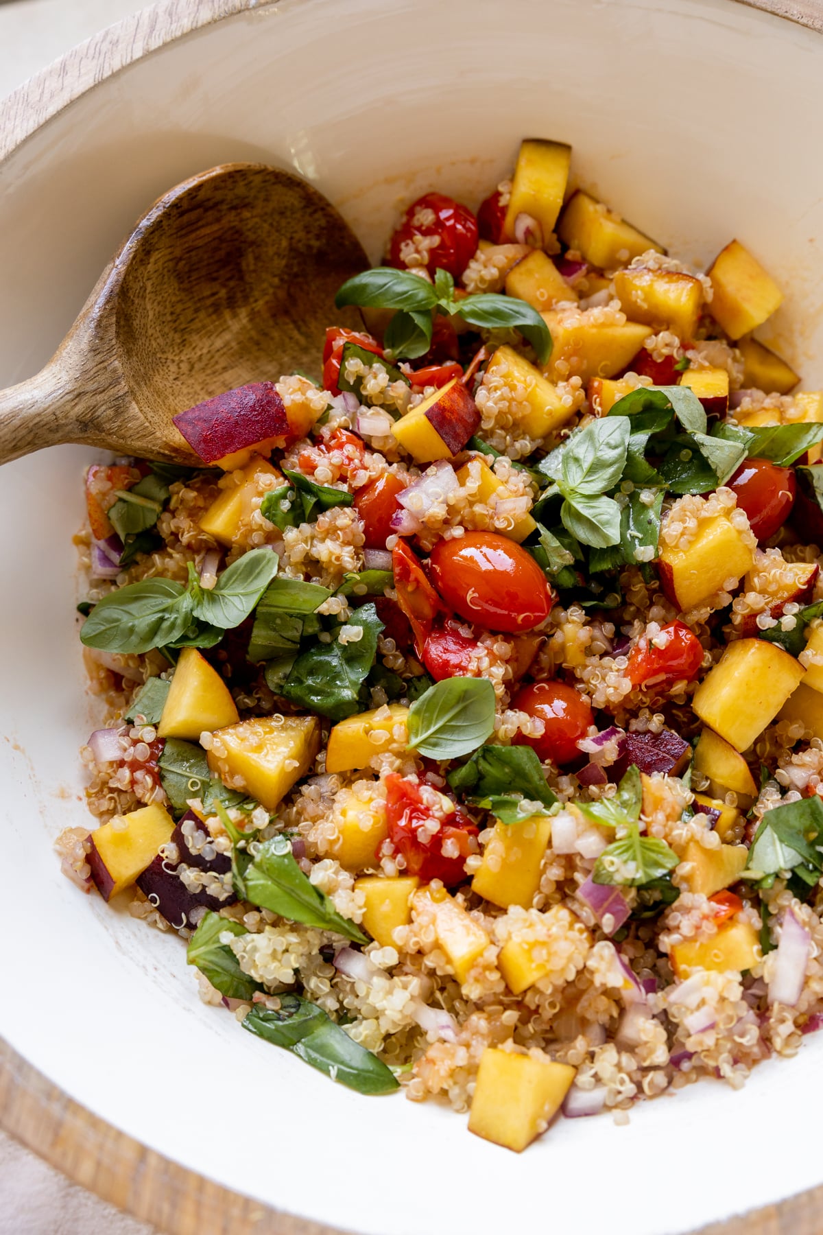 peach salad in a white bowl with fresh basil. 