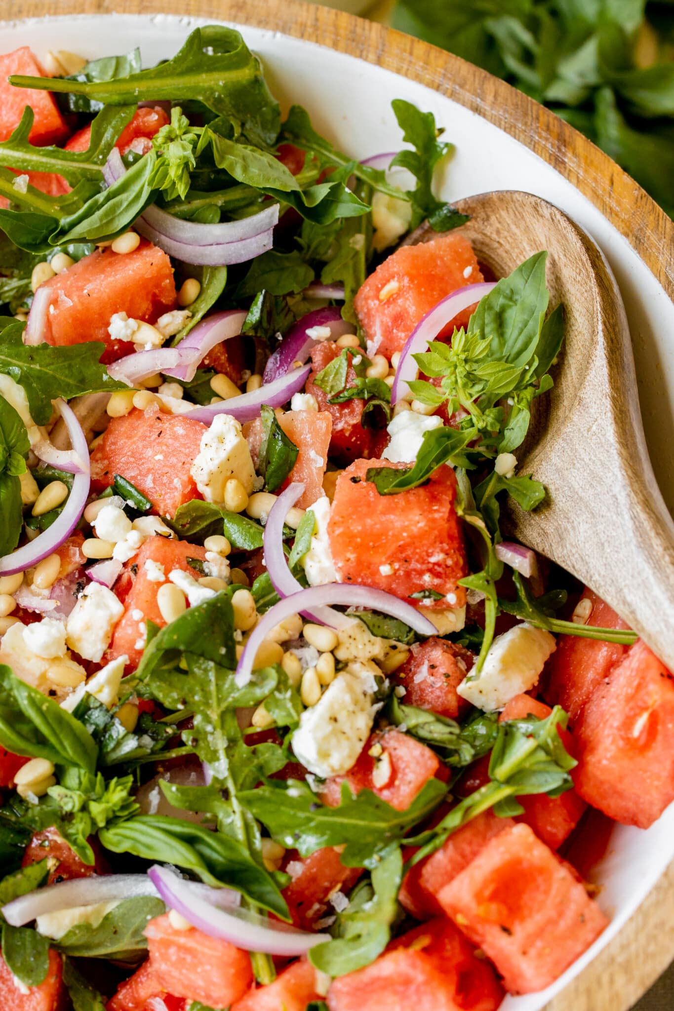 an up close image of a salad filled with feta, pine nuts, basil, and watermelon.
