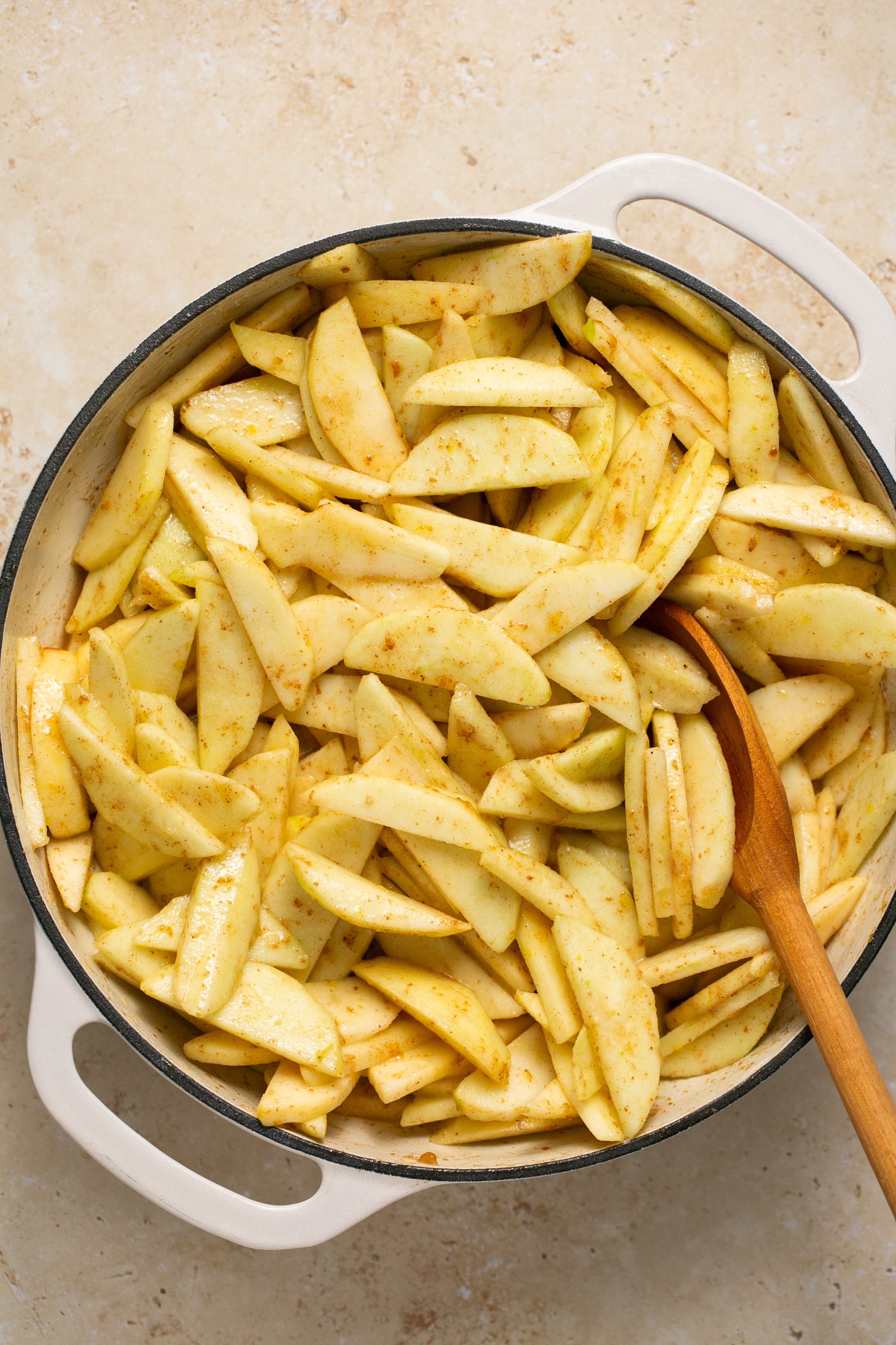 apples in a dutch oven with a wooden spoon. 
