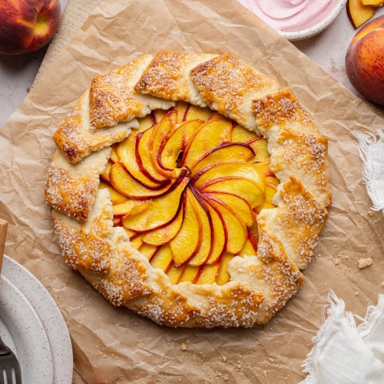 Peach galette chilling on piece of parchment paper after baking before serving.