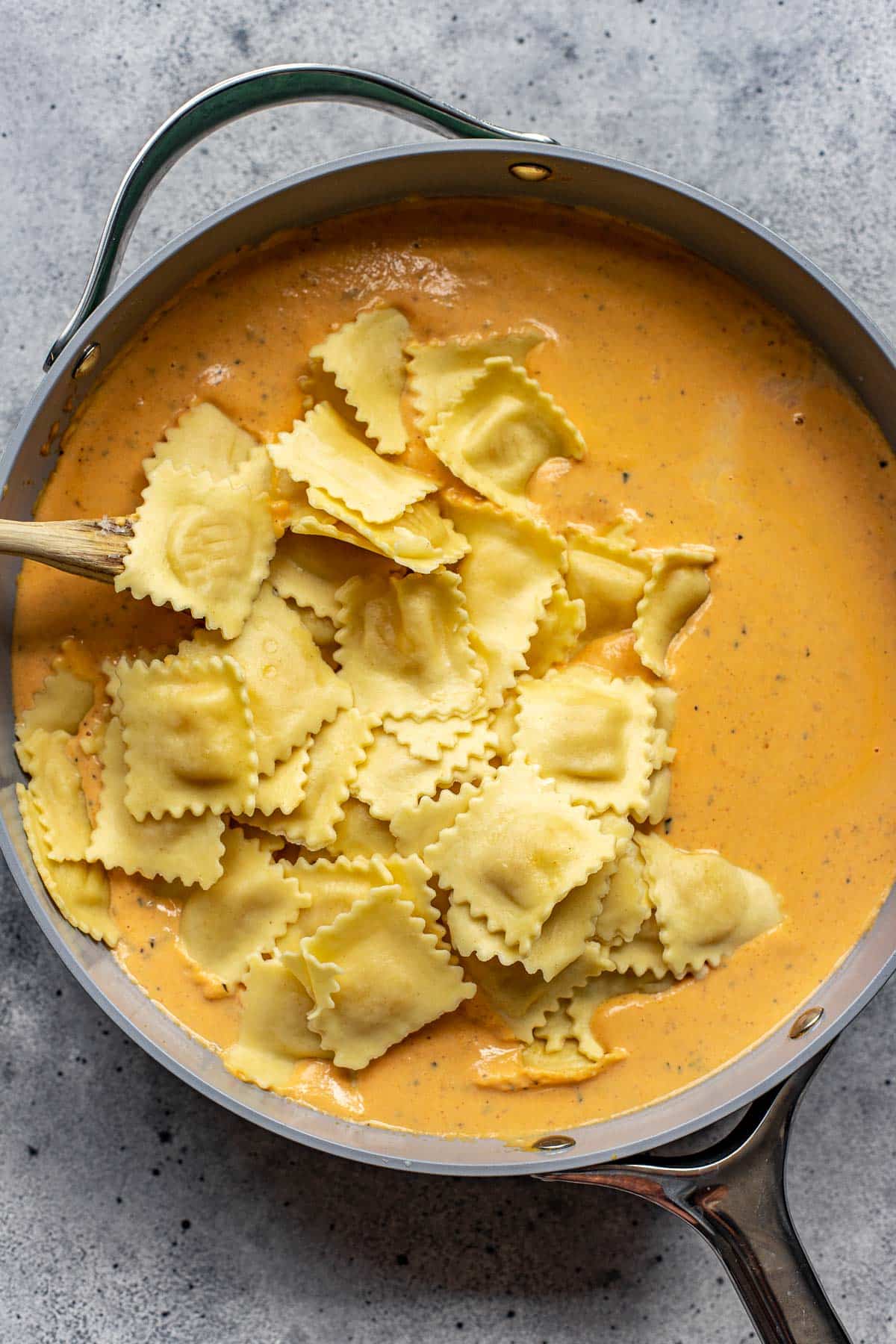 pumpkin alfredo sauce in a pan with cooked cheese ravioli. 