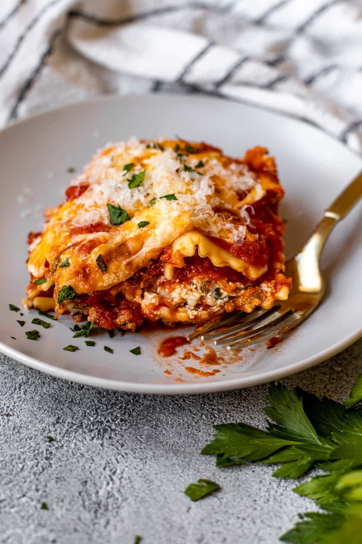 Ravioli with red sauce and cheese on a plate with a gold fork. 
