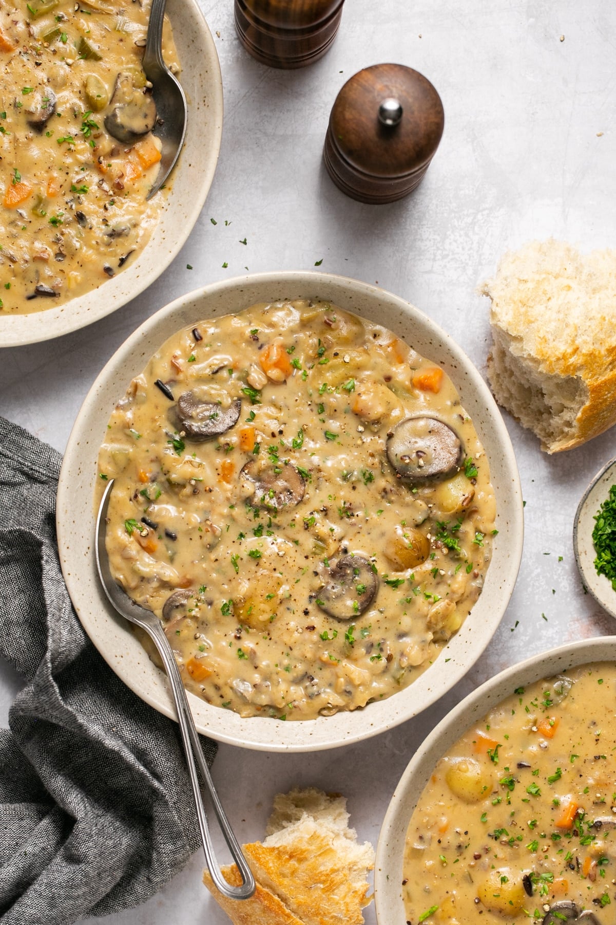 creamy soup in a white speckled bowl with parsley on top.