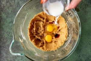 hand adding white ingredients to cookie dough mixture