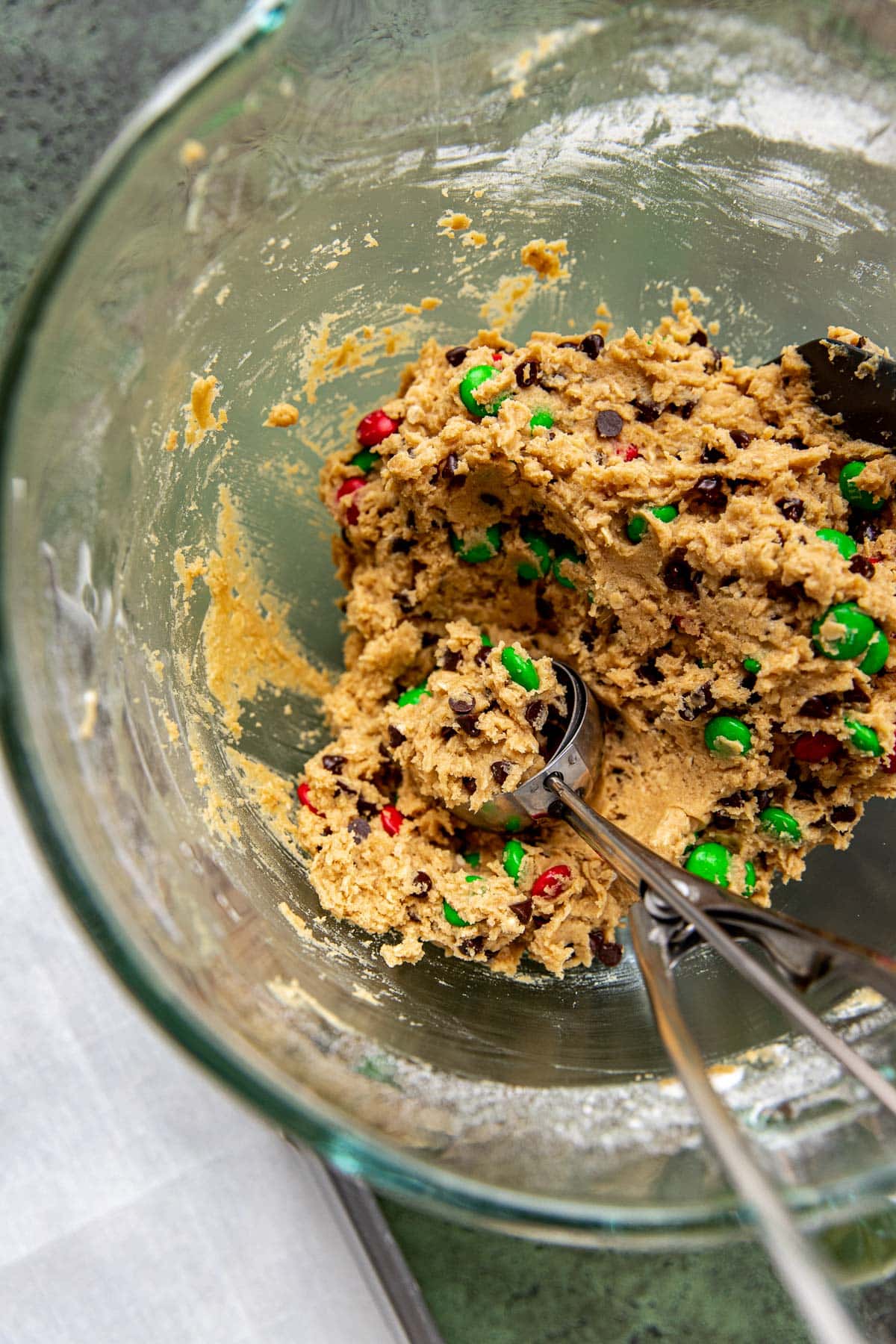 cookie dough with chocolate chips and M&Ms in a glass mixing bowl. 