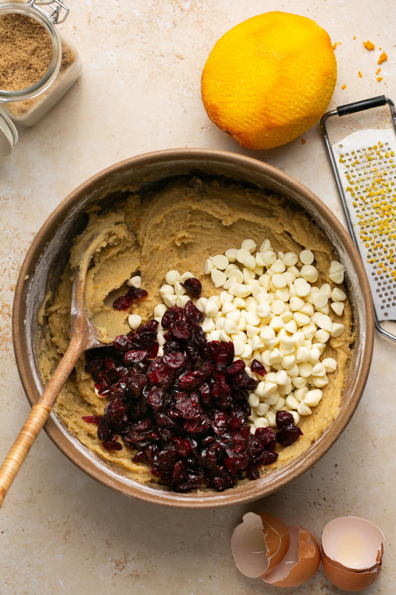 blondie batter in a mixing bowl with dried cranberries and white chocolate chips. 