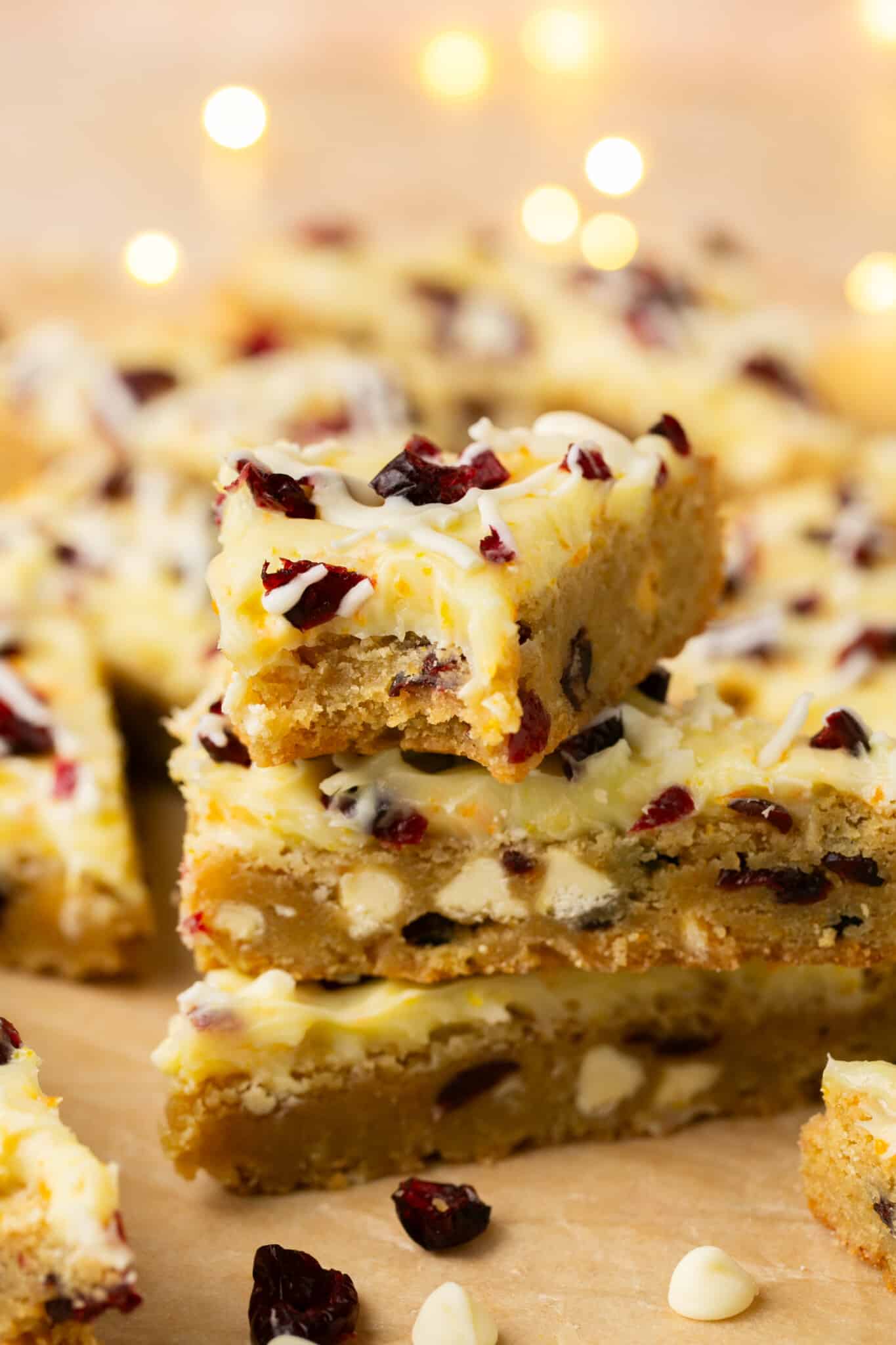 a bite taken out of a cookie bar made with dried cranberries and white chocolate chips with a cream cheese frosting. 