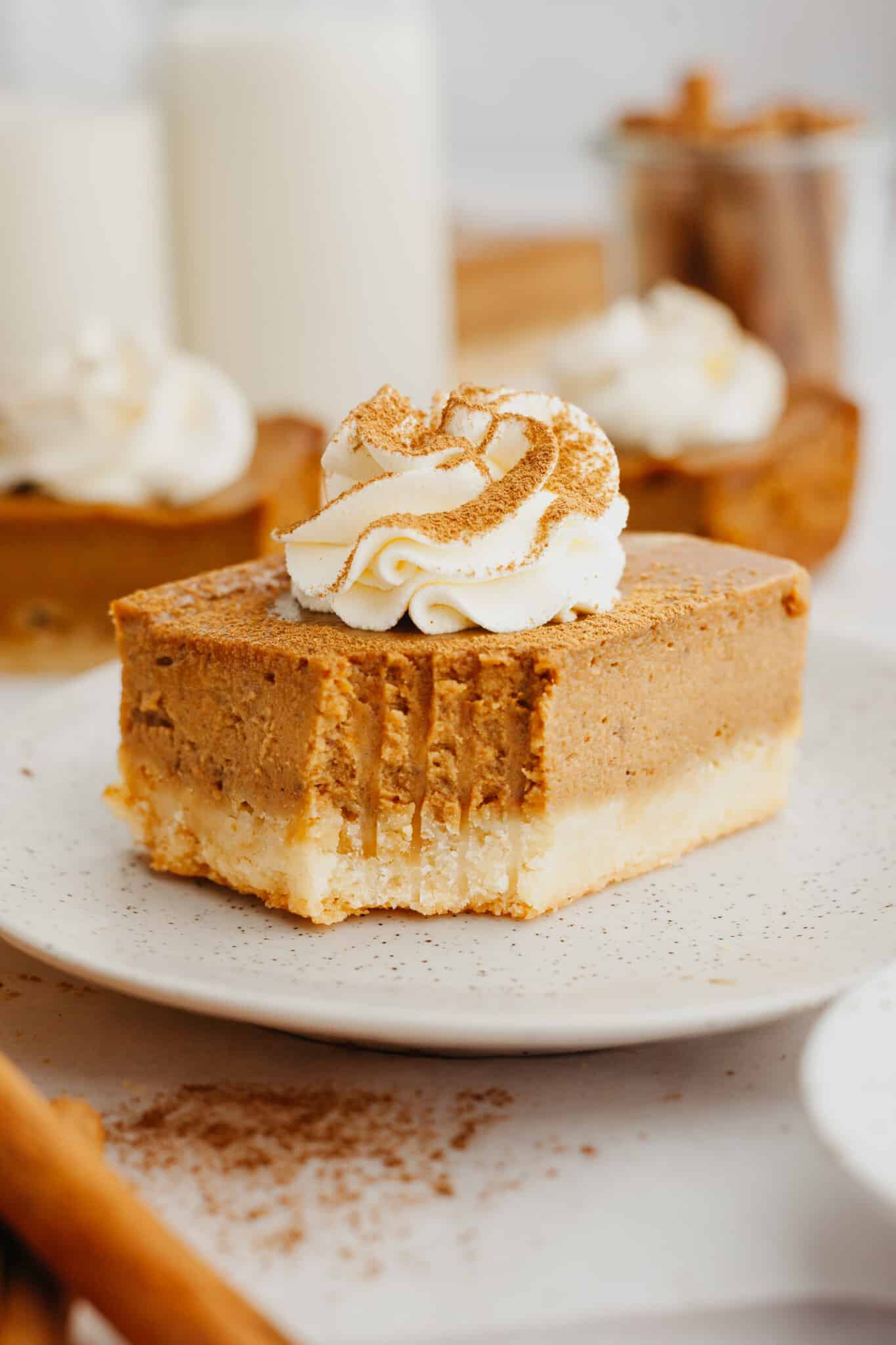 a bite taken out of a pumpkin pie bar topped with whipped cream.