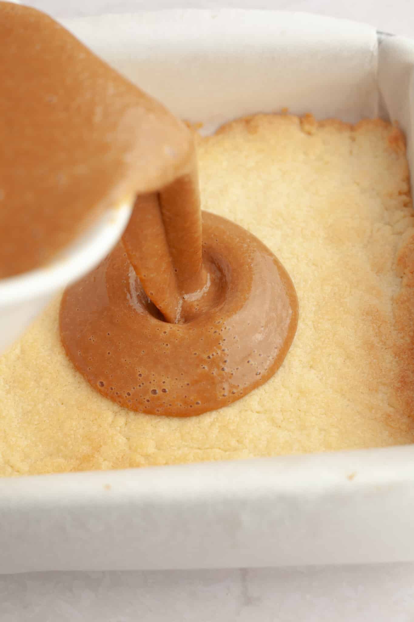 pumpkin pie filling being poured onto crust.
