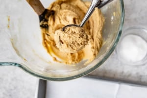 a cookie scoop removing cookie dough out of a clear bowl
