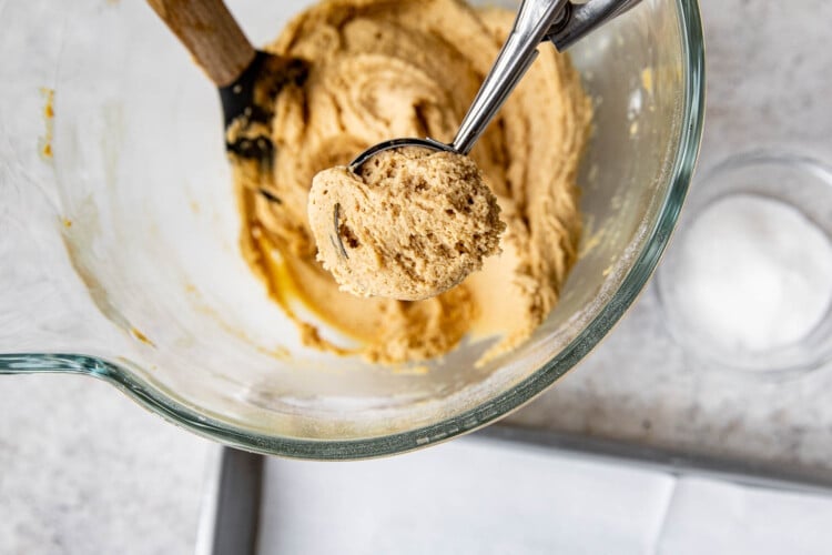 a cookie scoop removing cookie dough out of a clear bowl