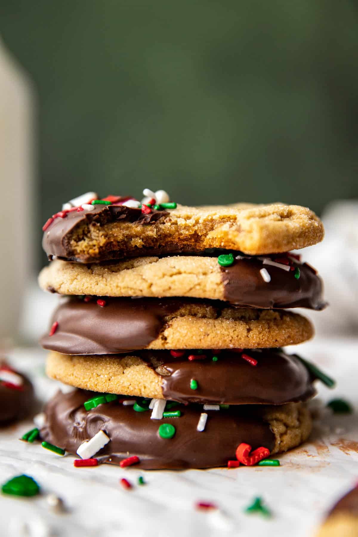 a stack of cookies dipped in dark chocolate with a bite taken out of the cookie on top of the stack. 
