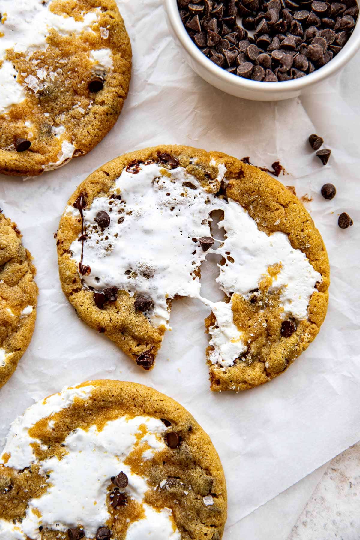 a peanut butter cookie on white parchment paper made with mini chocolate chips and marshmallow fluff in the center. 