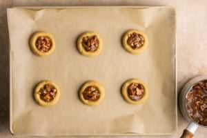 six cookies on a baking sheet topped with pecans