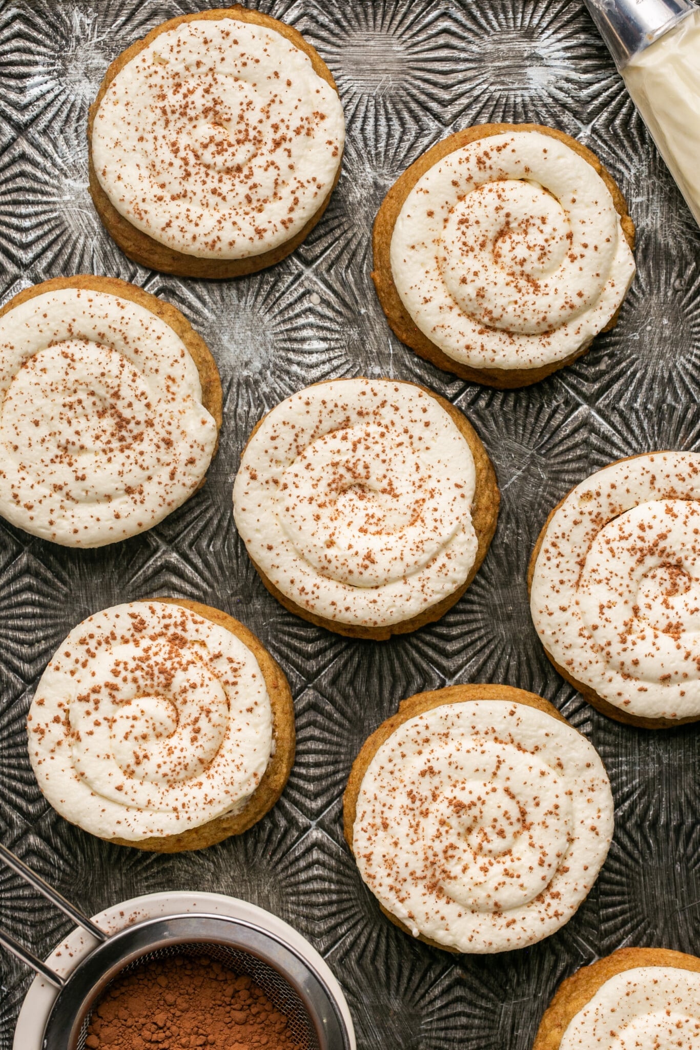multiple frosted tiramisu cookies sprinkled with cinnamon