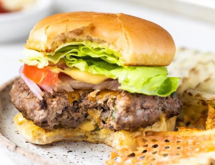 burger in a bun with lettuce and tomato on a plate