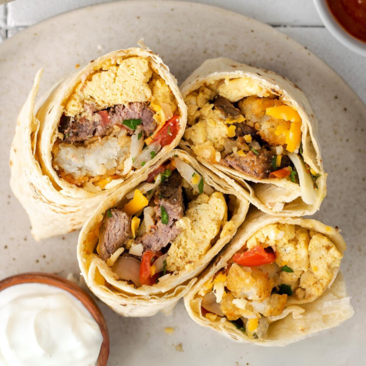 plate with halves of breakfast burritos and a side of sour cream