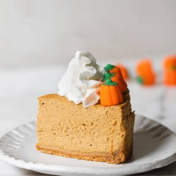 slice of pumpkin cheesecake with whipped cream and pumpkin candy
