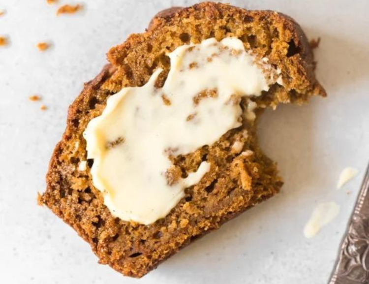 slice of pumpkin bread with butter spread, on a marble counter
