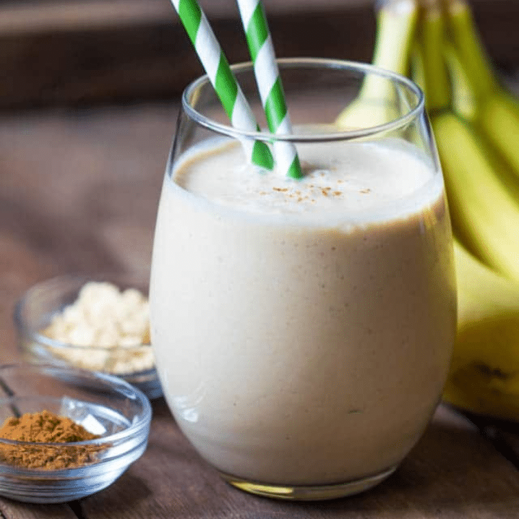 tan smoothie in a stemless wine glass with a green and white straw