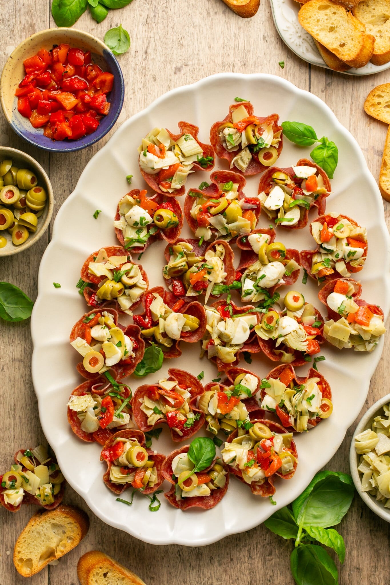 white plate with salami cups stuffed with artichokes olives cheese and roasted peppers