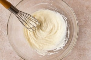 a clear bowl with whisk combining melted butter and suggar