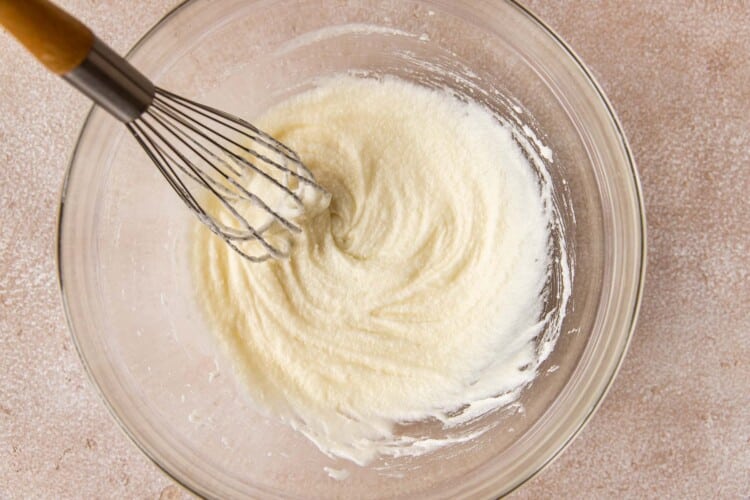a clear bowl with whisk combining melted butter and suggar