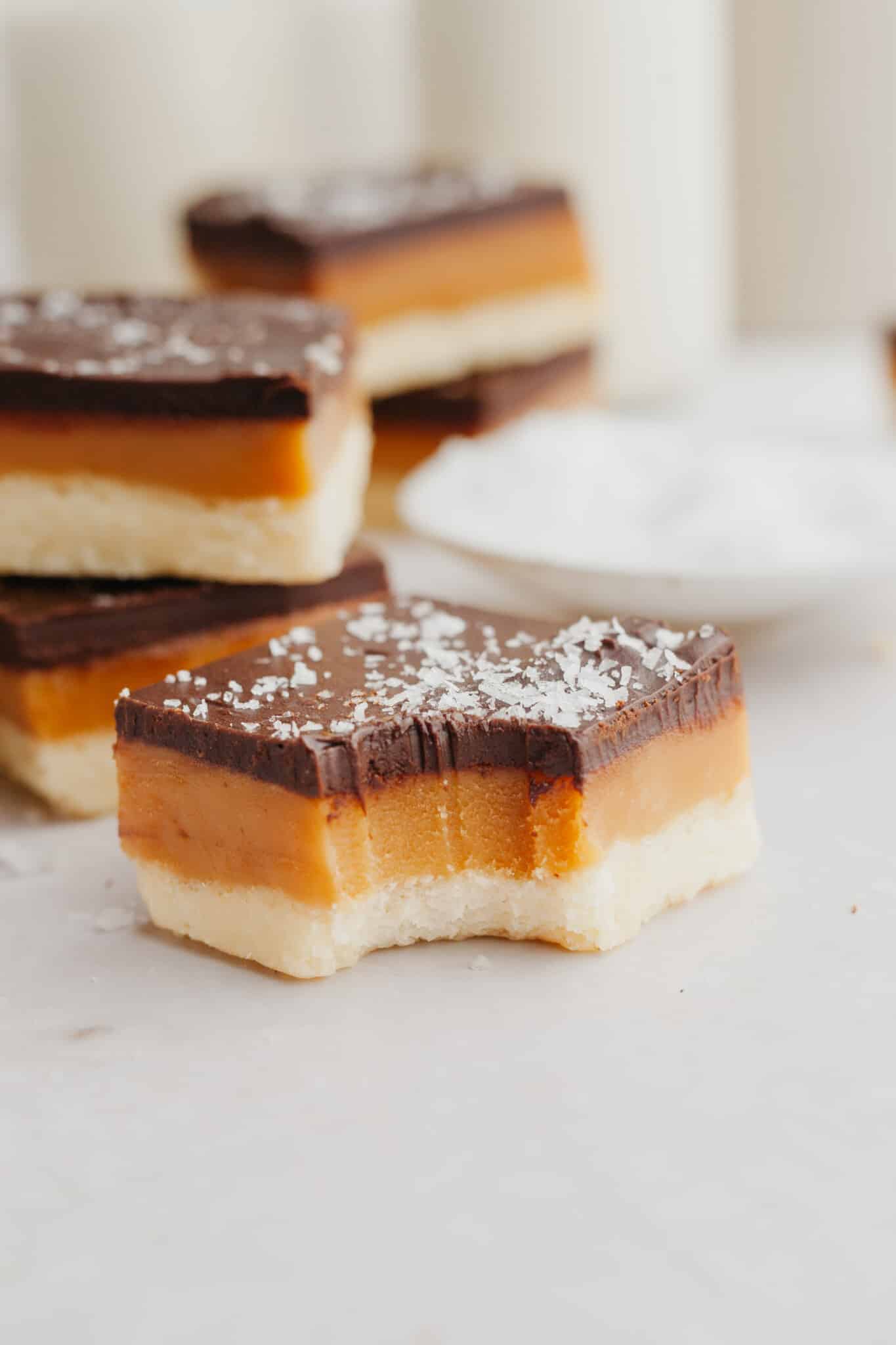 a bite taken out of a millionaires shortbread bar with flaky salt on top. 