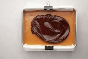 baking dish with shortbread bars and chocolate being spread on top