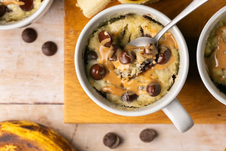 mug cake made with banana and chocolate chips with a drizzle of peanut butter on top.