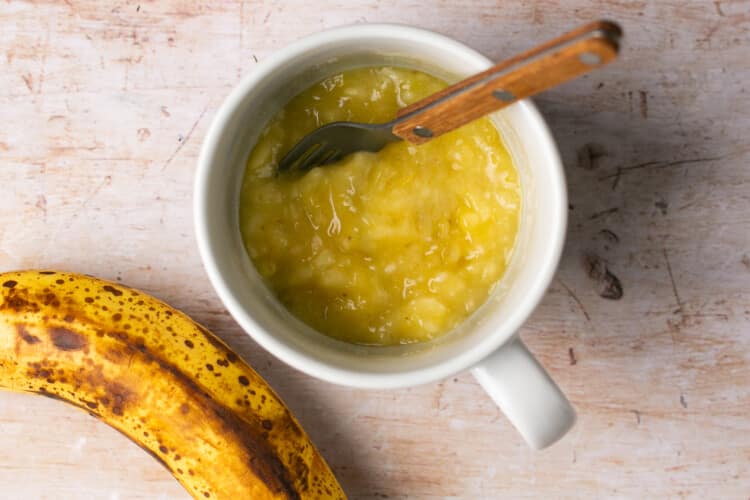 mashed banana in a white ceramic mug.