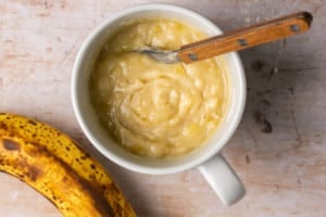 cake batter in a white ceramic mug with a fork in it.