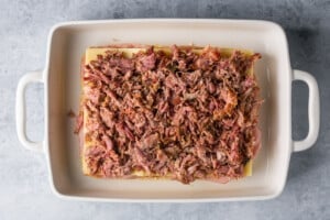 pulled pork on slider buns in a white baking dish.