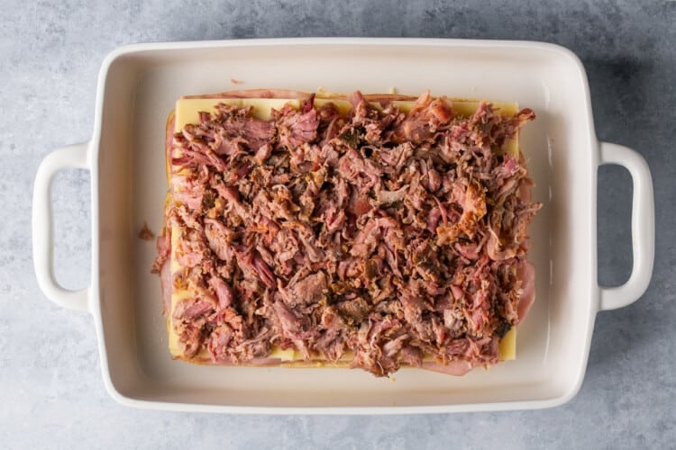 pulled pork on slider buns in a white baking dish.