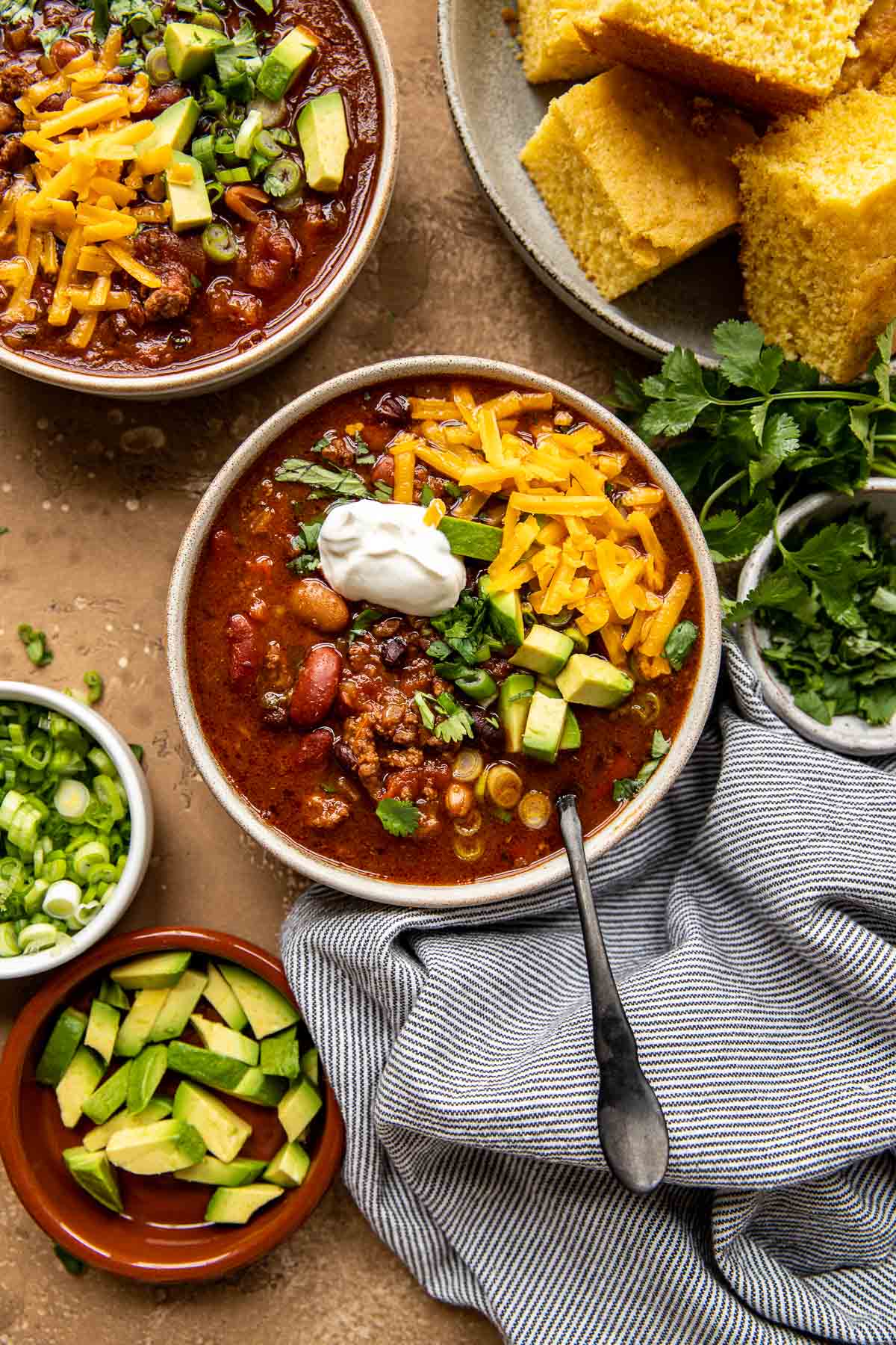 chili in a bowl with avocado, cheese, sour cream and cilantro. 