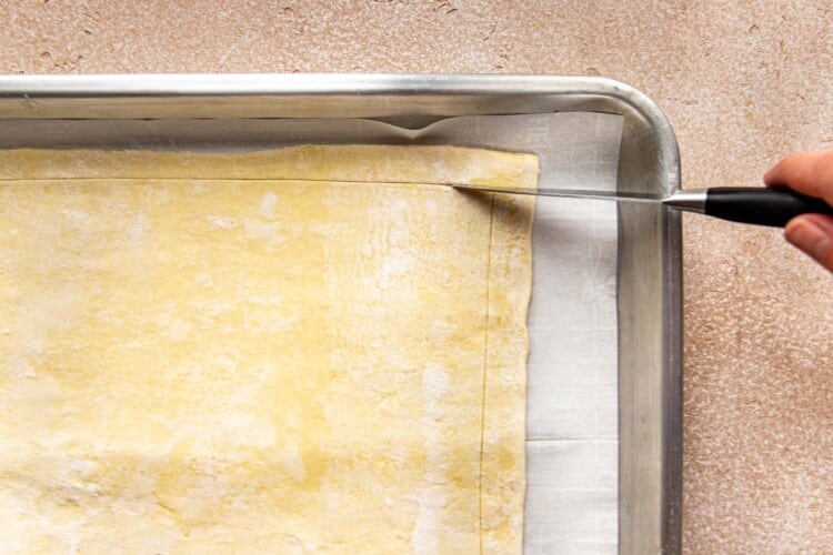 a knife scoring the edges of puff pastry dough.