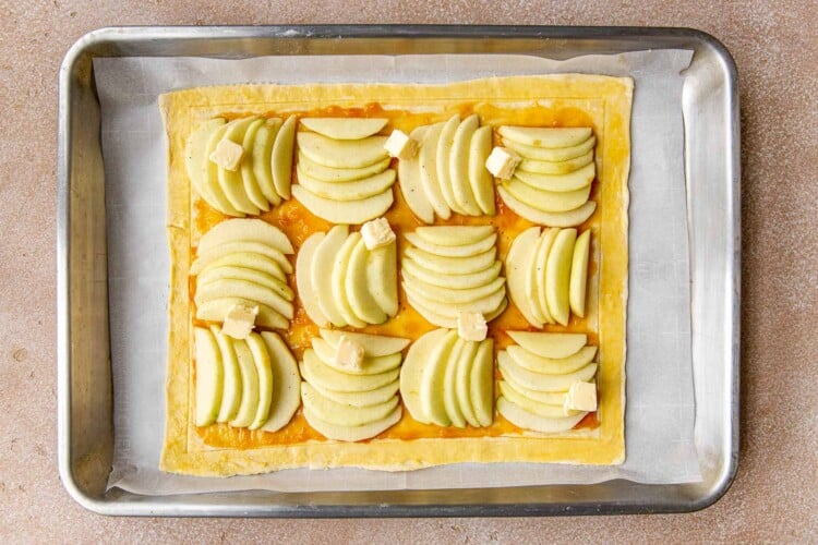 an apple tart on a baking sheet lined with parchment paper.