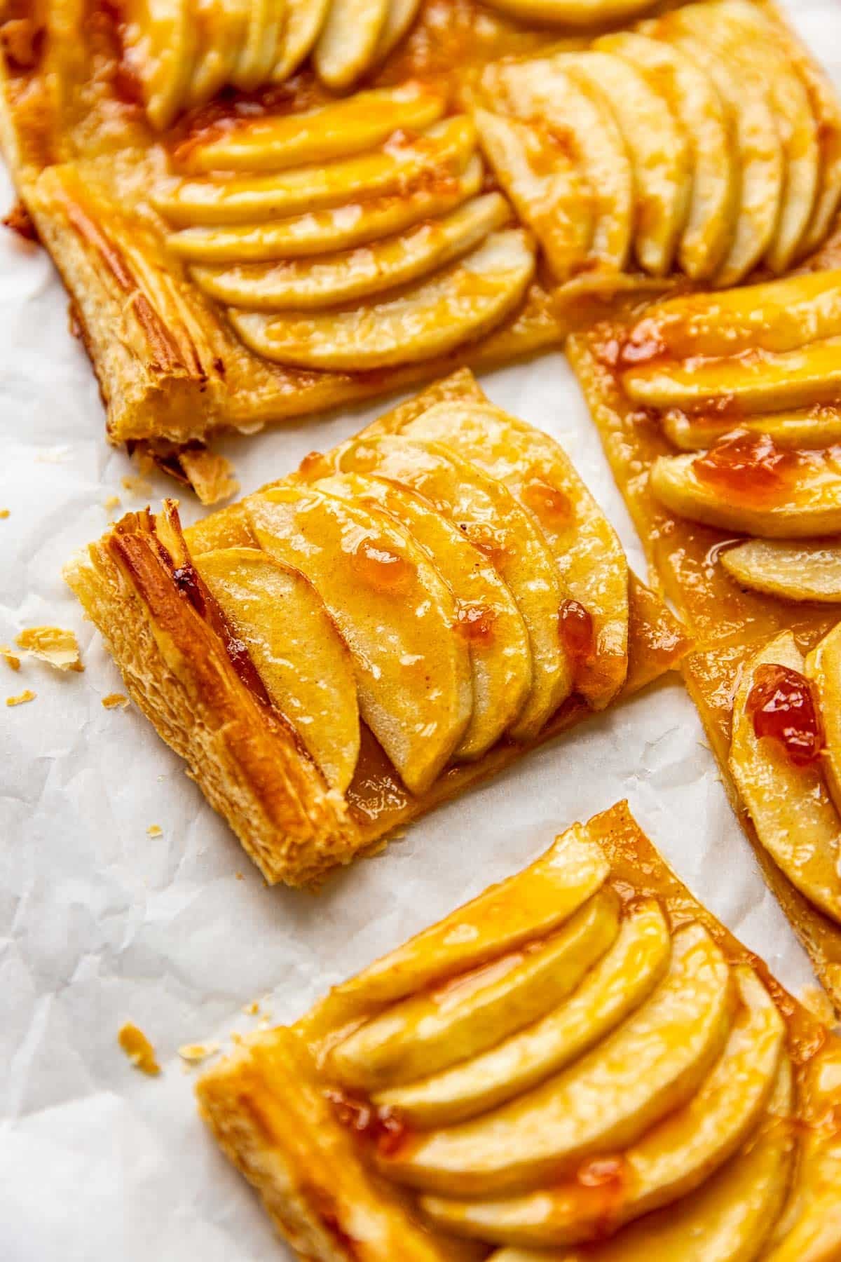 an up close image of an apple tart made with puff pastry and apricot preserves brushed on top. 