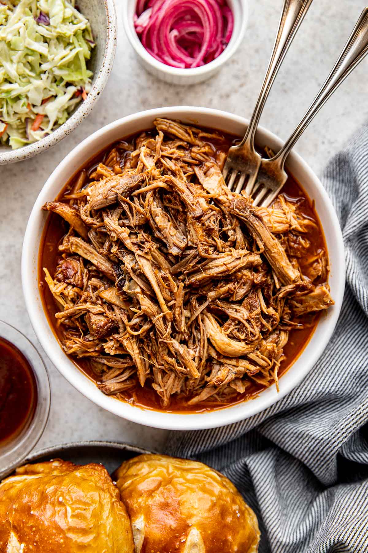 pulled pork in a white bowl with two forks.