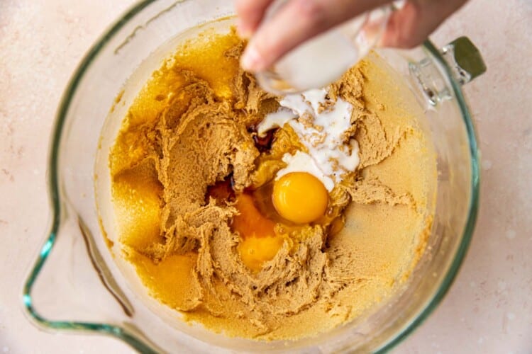 eggs being poured into creamed butter and sugars.