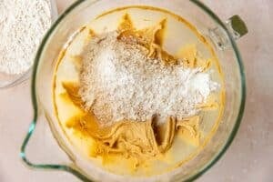 dry ingredients added into a mixing bowl to make cookie dough.
