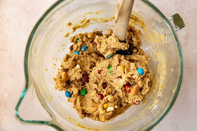a rubber spatula in cookie dough in a glass bowl.