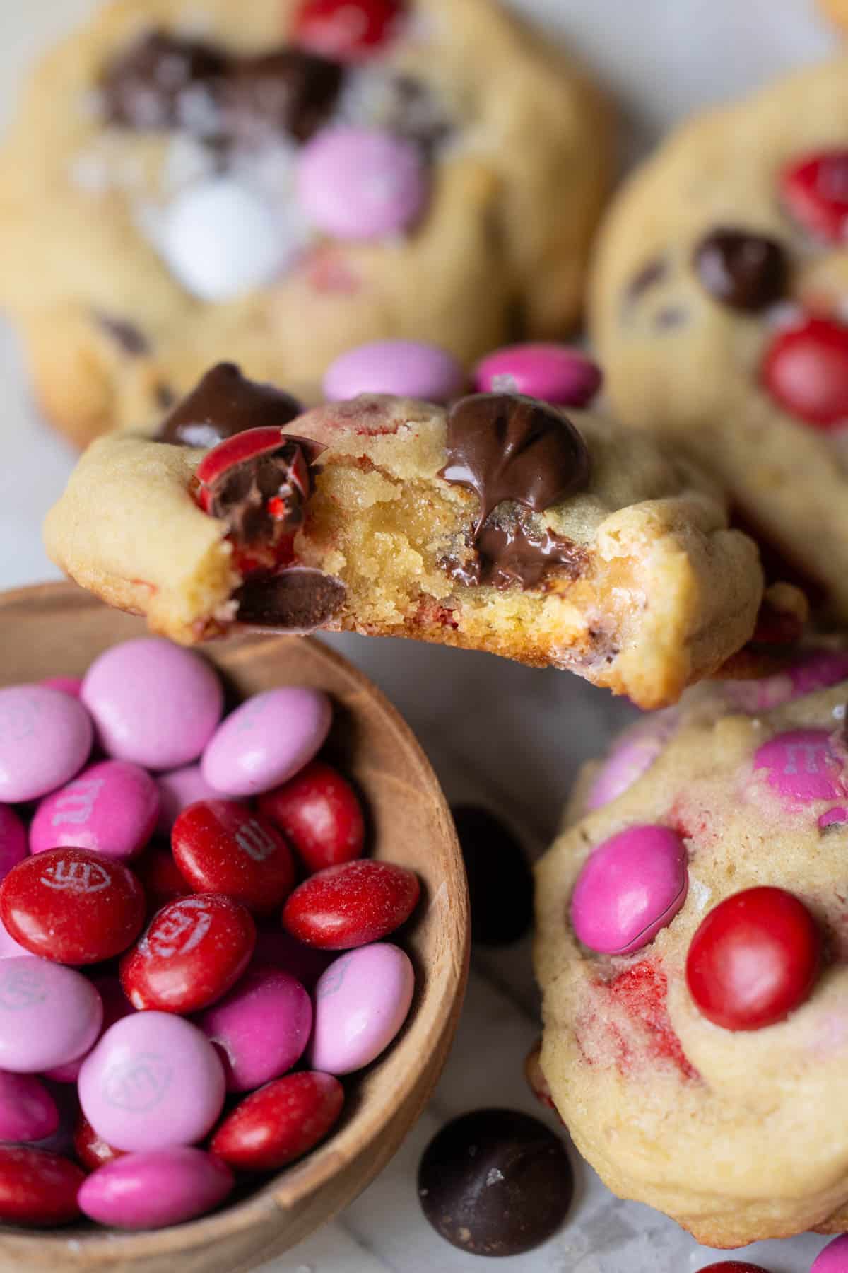an up close image of a bite taken out of a cookie made with M&Ms and chocolate chips. 