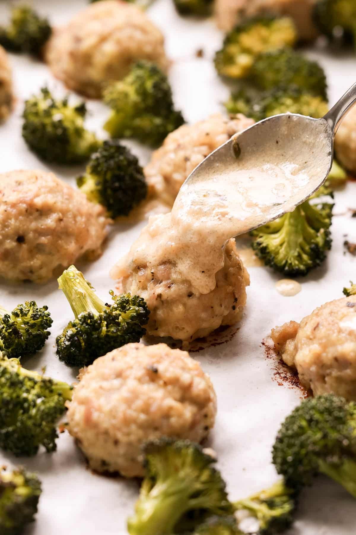 sauce being spooned onto a chicken meatball. 