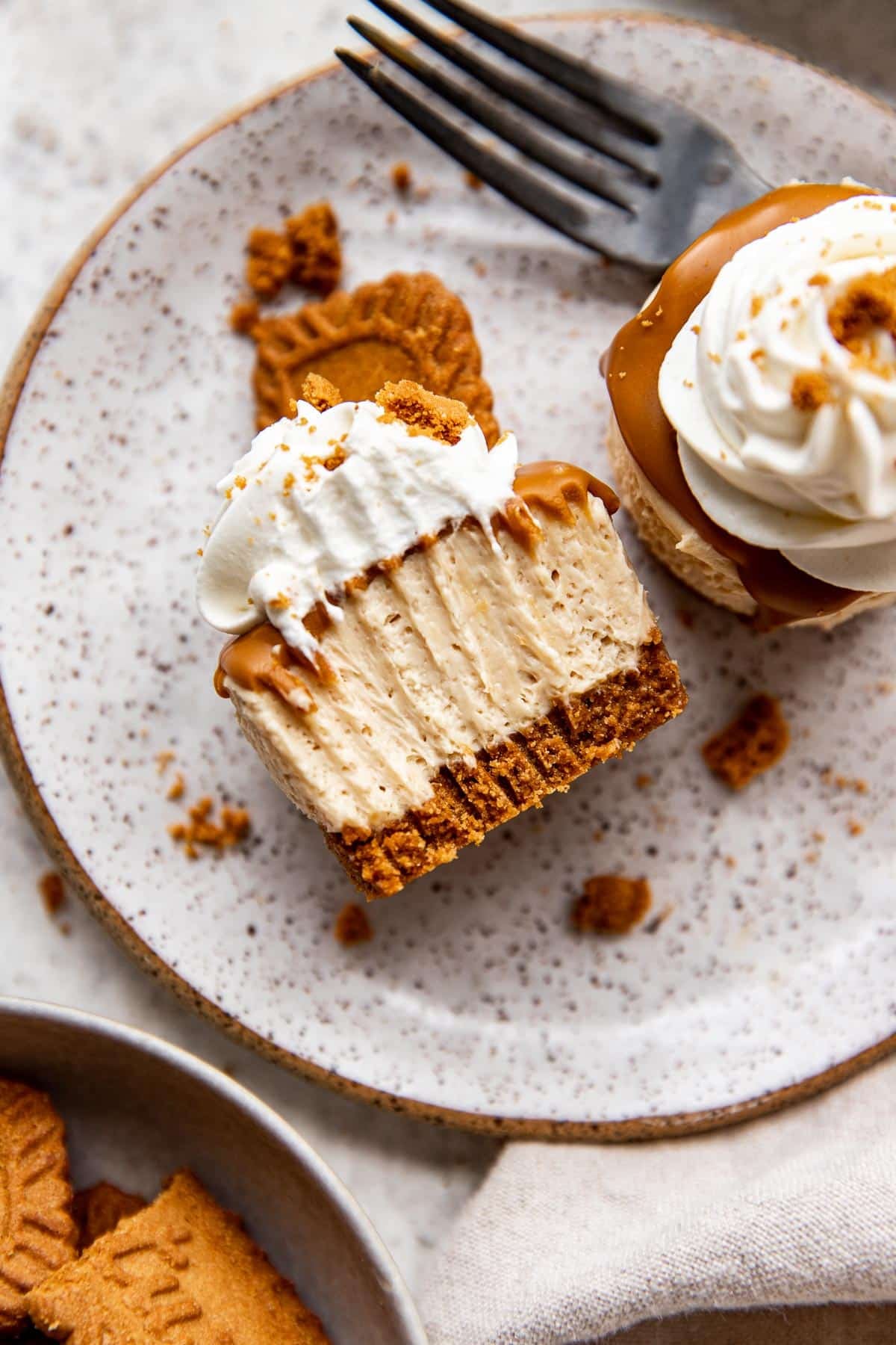 bite of a cheesecake garnished with whipped cream on a plate.